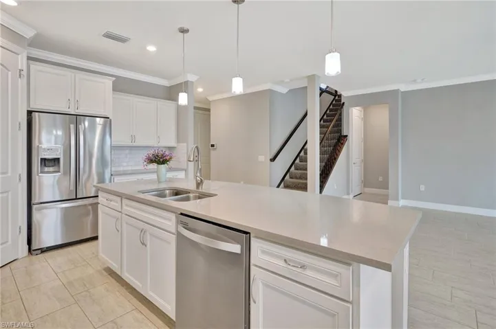 Kitchen with decorative backsplash, visible vents, crown molding, a sink, and stainless steel appliances