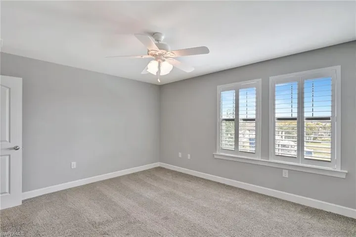 Carpeted empty room with baseboards and a ceiling fan