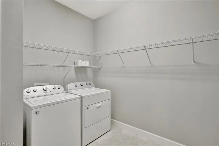 Clothes washing area featuring baseboards, laundry area, and washing machine and clothes dryer