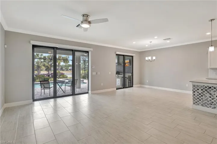 Unfurnished living room featuring crown molding, baseboards, ceiling fan with notable chandelier, and recessed lighting