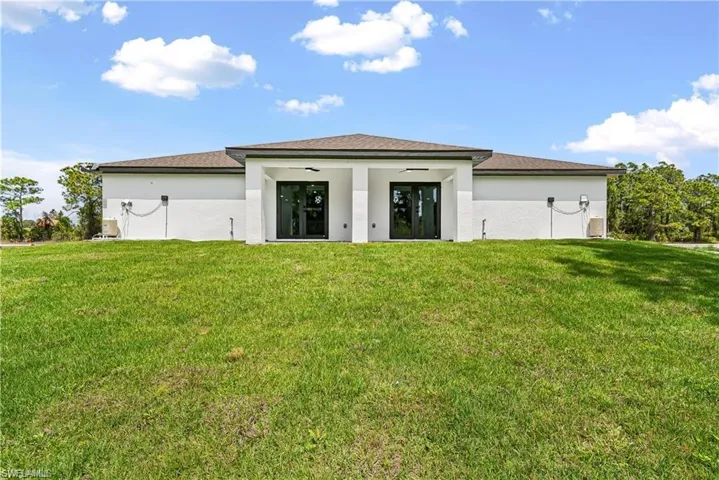 Modern structure featuring a symmetrical facade with white stucco exterior and a brown shingle roof