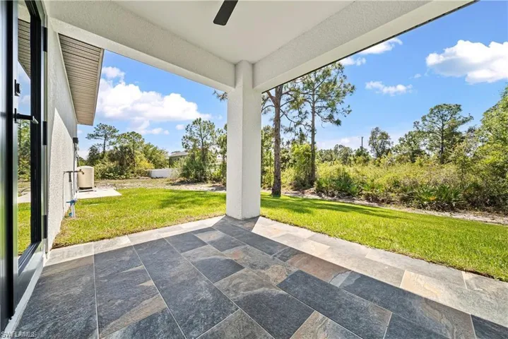 Covered patio featuring large format multi-tone floor tiles and a ceiling fan