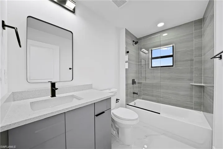 Contemporary bathroom featuring a light gray vanity with a built-in rectangular sink and a speckled white countertop