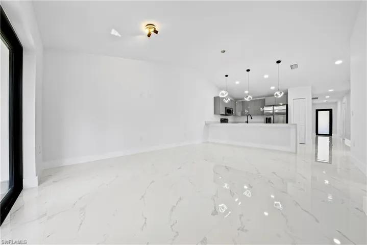 Spacious open-concept living area featuring large format tile flooring and a modern kitchen
