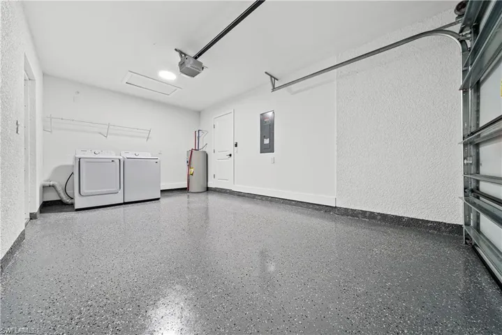 Spacious garage featuring a speckled epoxy floor, bright white walls, and a large overhead garage door