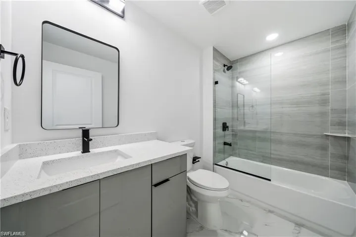 Contemporary bathroom featuring a white vanity with an integrated rectangular sink, matte black faucet, and a black-framed mirror