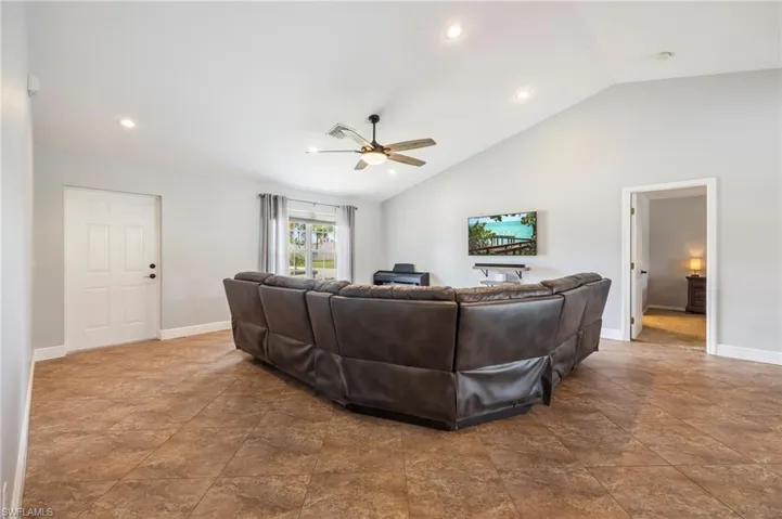 Spacious living area featuring vaulted ceilings, recessed lighting, tile flooring, and a ceiling fan