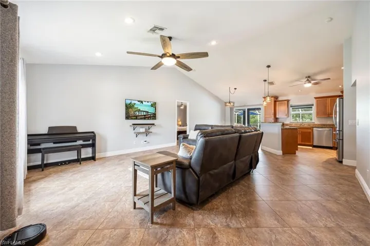 Open-concept living area featuring vaulted ceilings, recessed lighting, and tile flooring