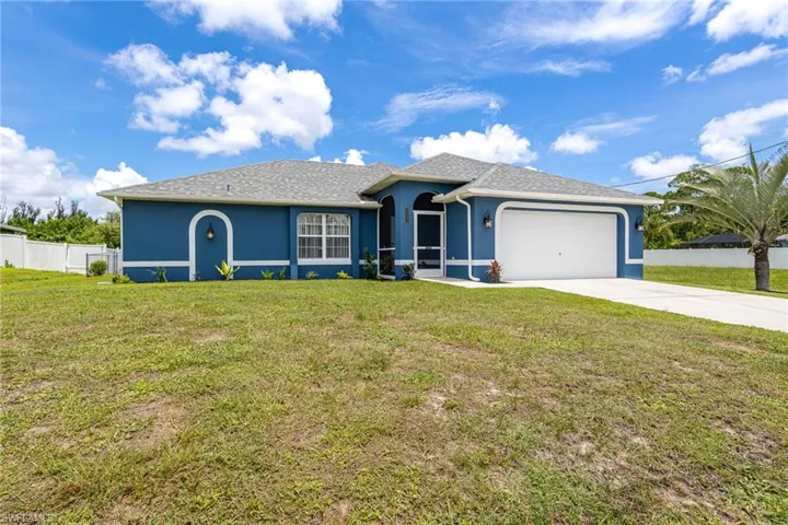Single-story residence featuring a blue exterior with white trim, an attached two-car garage, a screened front entry, and a paved driveway