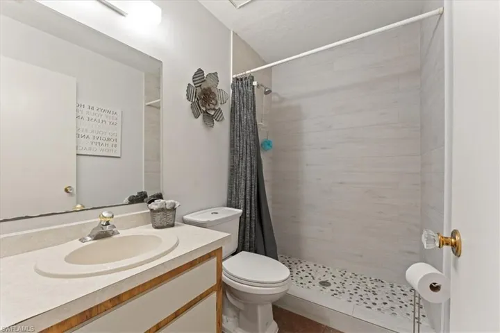 Bathroom featuring a stall shower, toilet, and vanity