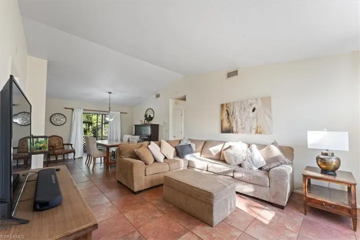 Living area with light tile patterned floors, visible vents, and lofted ceiling