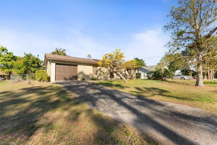 View of front facade with a front yard, fence, driveway, stucco siding, and a garage