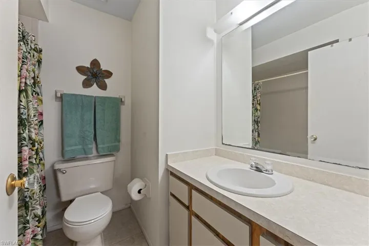 Bathroom featuring vanity, tile patterned floors, curtained shower, and toilet