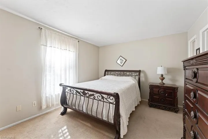Carpeted bedroom featuring baseboards and multiple windows