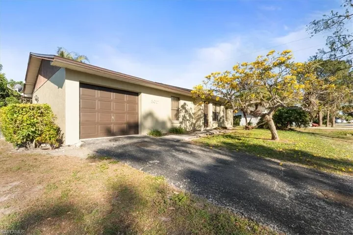 View of front facade featuring a front yard, a garage, driveway, and stucco siding