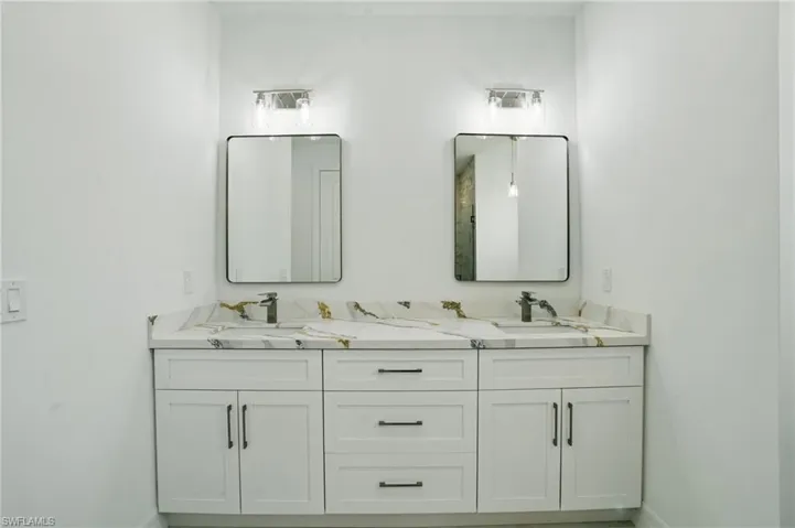 Full bath featuring double vanity and baseboards