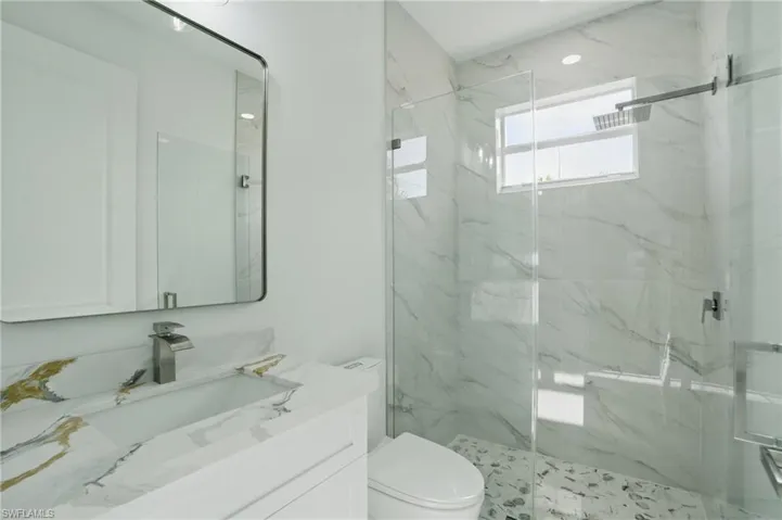 Bathroom featuring a marble finish shower and vanity