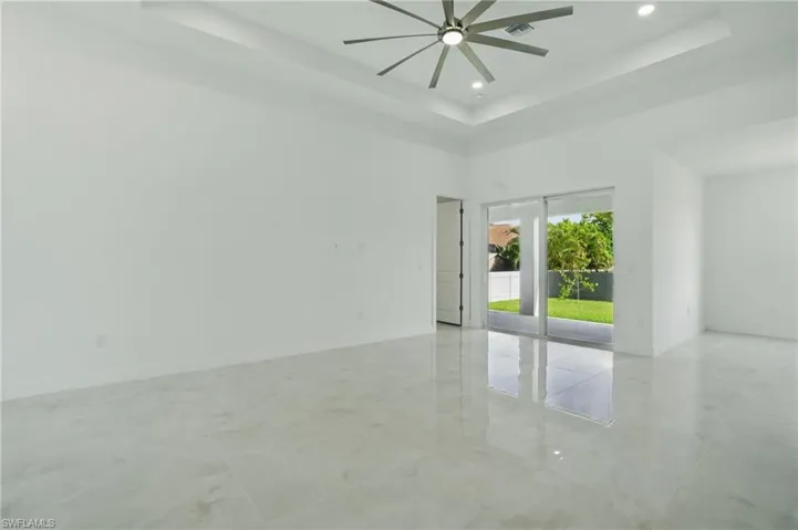 Empty room featuring ceiling fan, a tray ceiling, recessed lighting, and a towering ceiling