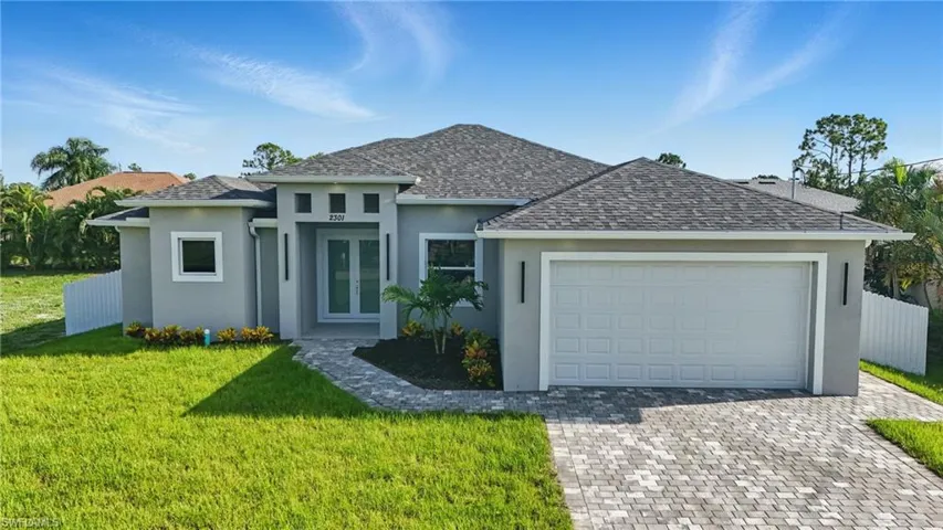 View of front facade with stucco siding, french doors, decorative driveway, and an attached garage