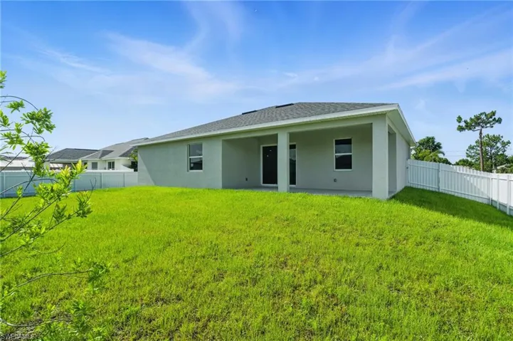 Back of property with stucco siding, a fenced backyard, and a shingled roof