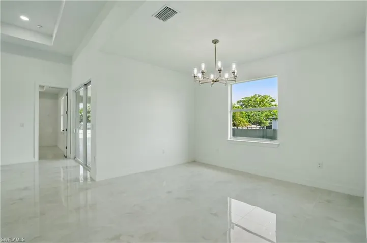 Spare room featuring healthy amount of natural light and a chandelier