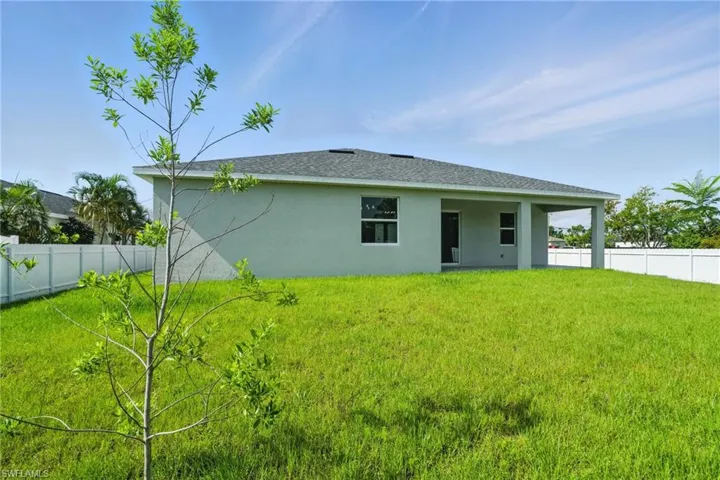 Rear view of house with stucco siding and a fenced backyard