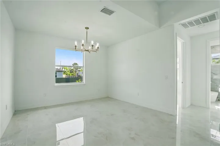 Unfurnished room featuring a chandelier and baseboards