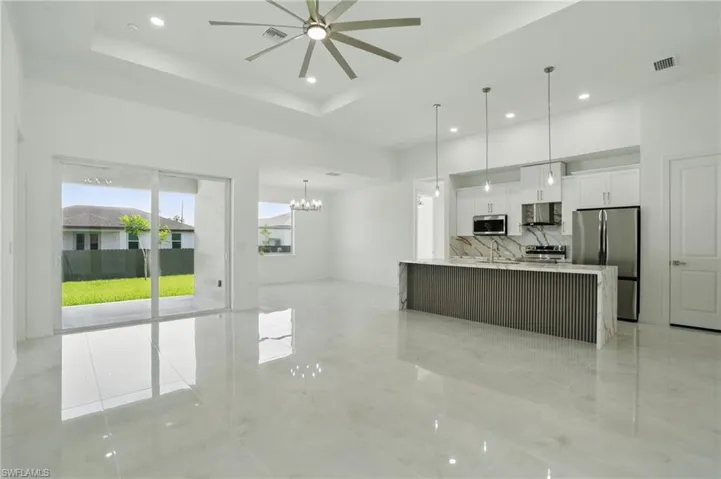 Kitchen with appliances with stainless steel finishes, ceiling fan, white cabinets, open floor plan, and exhaust hood