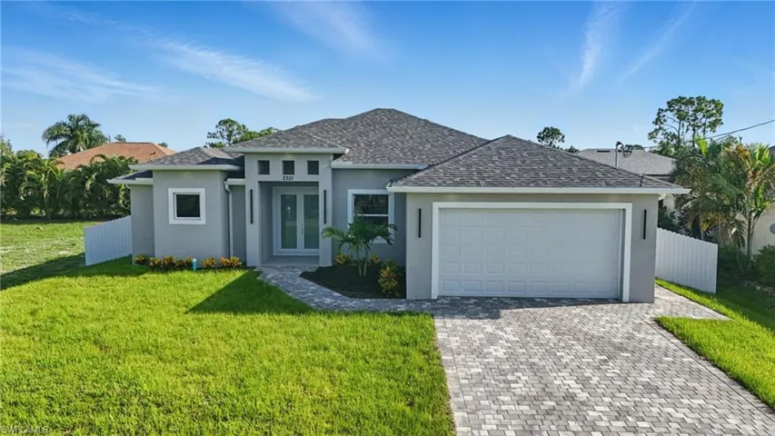 View of front of house featuring stucco siding, decorative driveway, a garage, roof with shingles, and french doors