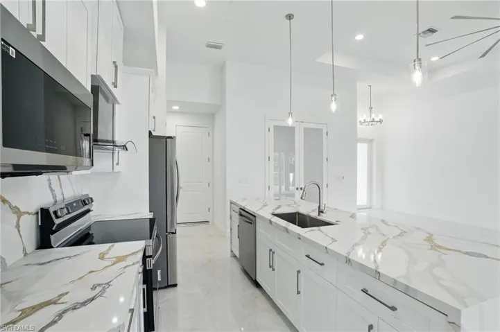 Kitchen with stainless steel appliances, white cabinetry, recessed lighting, and hanging light fixtures