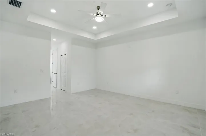 Empty room featuring a raised ceiling, recessed lighting, a smoke detector, and a ceiling fan
