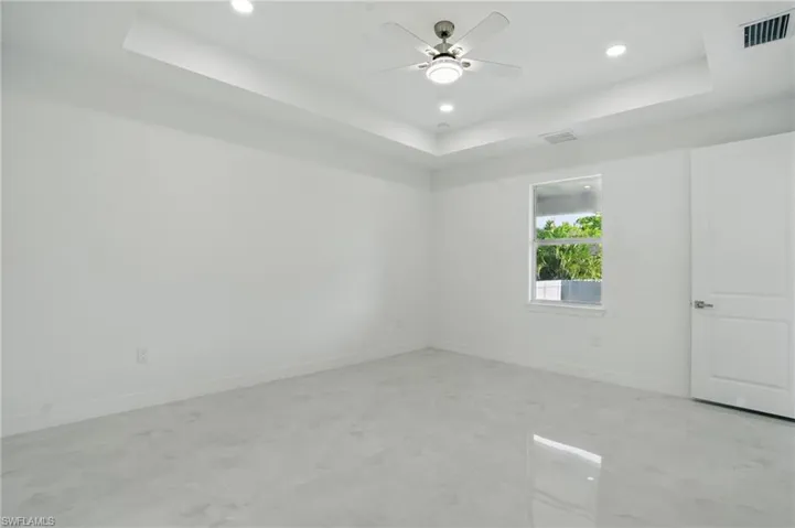Empty room with a raised ceiling, a ceiling fan, and recessed lighting