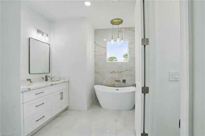 Full bathroom featuring vanity, a freestanding tub, and marble finish floors