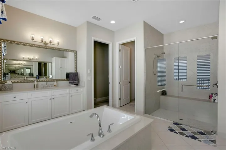 Bathroom featuring a stall shower, vanity, a garden tub, tile patterned flooring, and visible vents