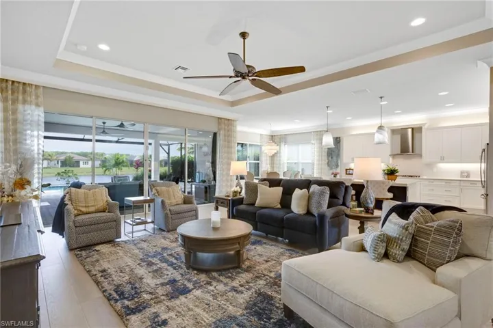 Living room with plenty of natural light, ornamental molding, a tray ceiling, and a ceiling fan