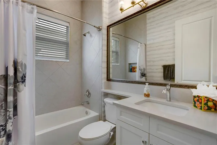 Full bath with toilet, vanity, and shower / tub combo with curtain