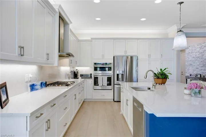 Kitchen with appliances with stainless steel finishes, light wood-type flooring, ornamental molding, and a sink