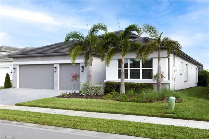 View of front facade featuring a tile roof, stucco siding, a garage, and a front lawn