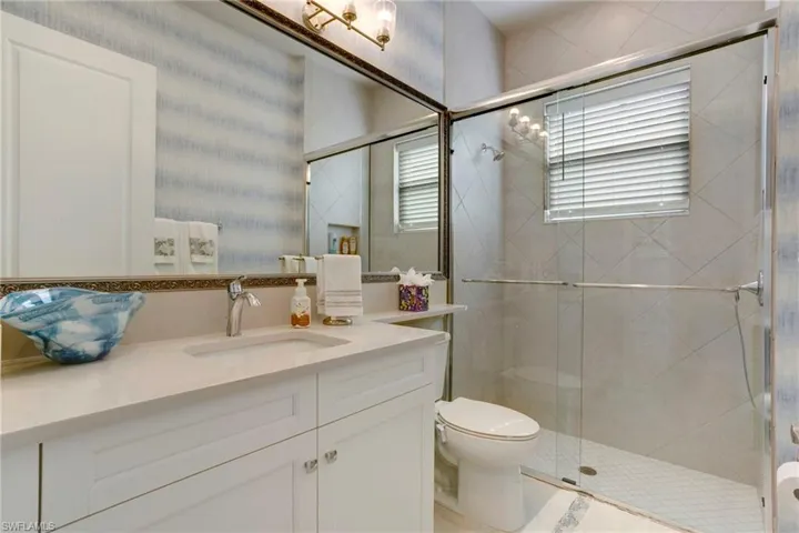 Bathroom featuring vanity, toilet, and a shower stall