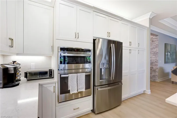 Kitchen featuring white cabinets, light stone countertops, appliances with stainless steel finishes, and a toaster