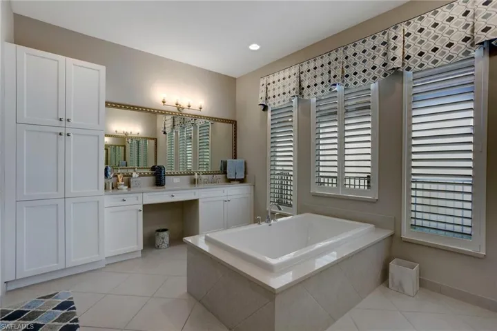 Carpeted primary bedroom featuring a ceiling fan, a tray ceiling, and baseboards