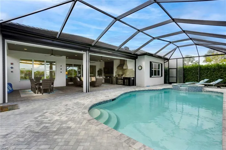 View of swimming pool with exterior kitchen, a pool with connected hot tub, a patio, ceiling fan, and outdoor dining space