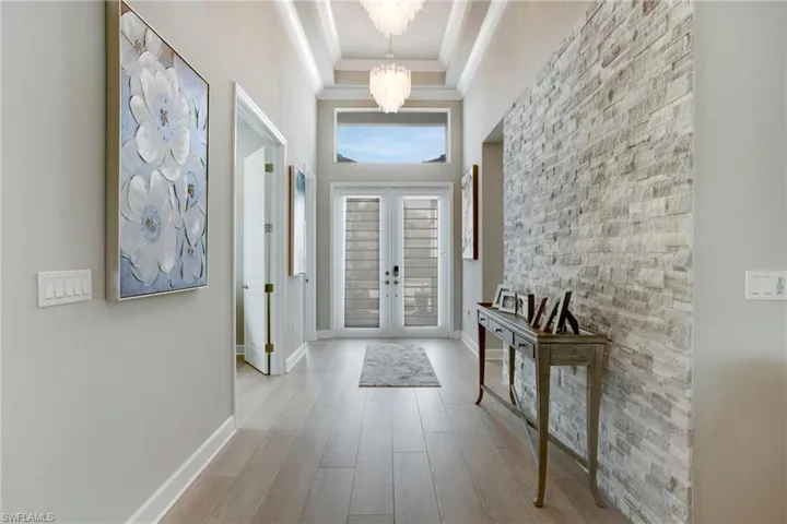 Foyer featuring crown molding, baseboards, a towering ceiling, a notable chandelier, and wood finished floors
