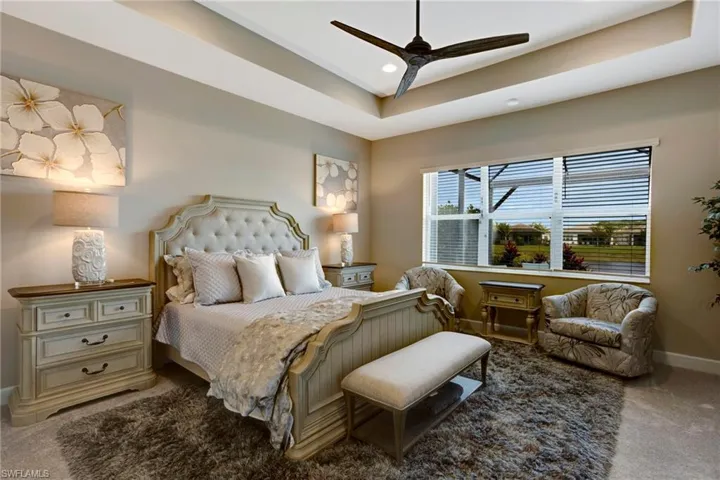 Bedroom with baseboards, carpet floors, a ceiling fan, and a raised ceiling