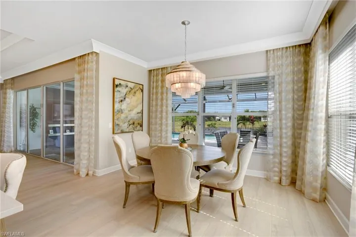 Dining space with plenty of natural light, baseboards, light wood-style flooring, and an inviting chandelier