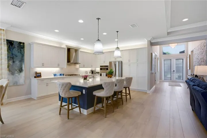 Kitchen with a sink, wall chimney exhaust hood, a kitchen breakfast bar, stainless steel appliances, and visible vents