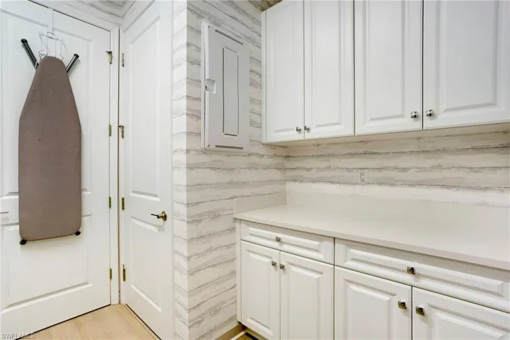 Clothes washing area with light wood finished floors