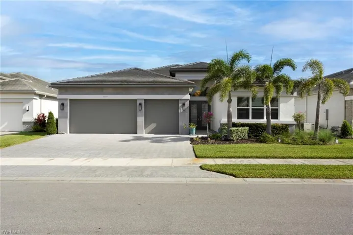View of front of house featuring stucco siding, a tile roof, a garage, and decorative driveway