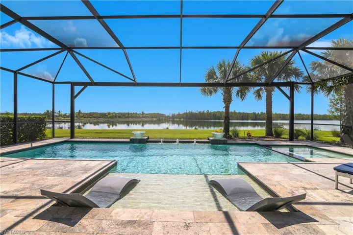 Enjoy stunning views from your private lanai with custom pool featuring pool with integrated spa, sun shelf, glass fountain bowls, travertine tile deck, and panoramic screen with unobstructed views of Indigo Lake and protected preserve.