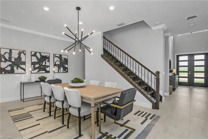 Formal dining area includes crown molding, designer lighting, and gorgeous open staircase leading to the upper loft and addational bedroom/bath.